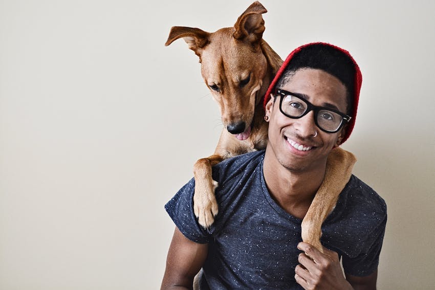 A male pet owner helping his dog with canine holiday anxiety by holding him on his shoulder.